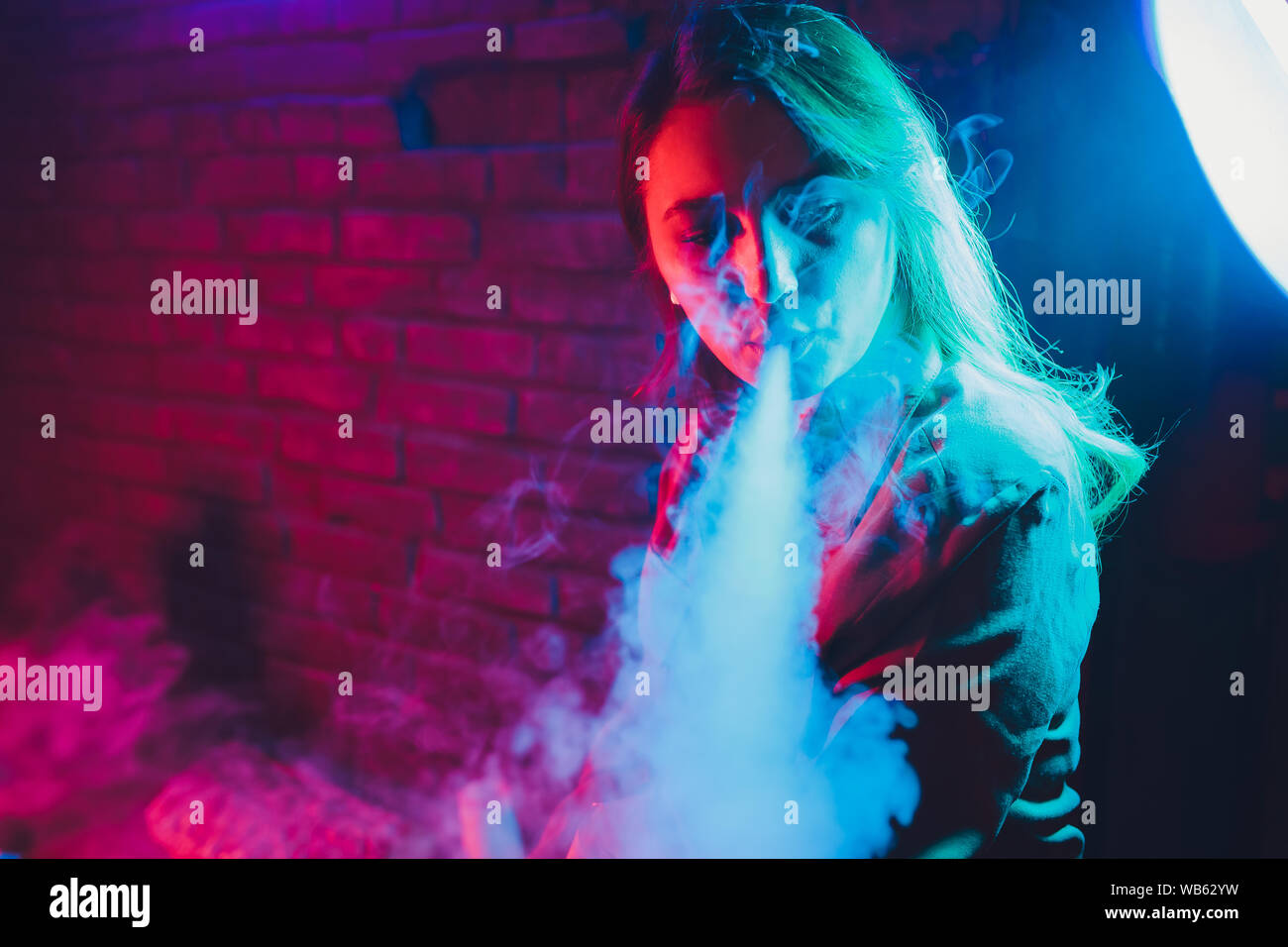 Femme fume une e-cigarette allongé sur le lit dans la chambre. Concept du  fumeur Vaping Photo Stock
