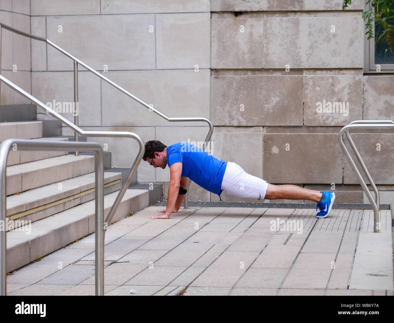 Man doing pushups en public. Chicago Riverwalk. Banque D'Images