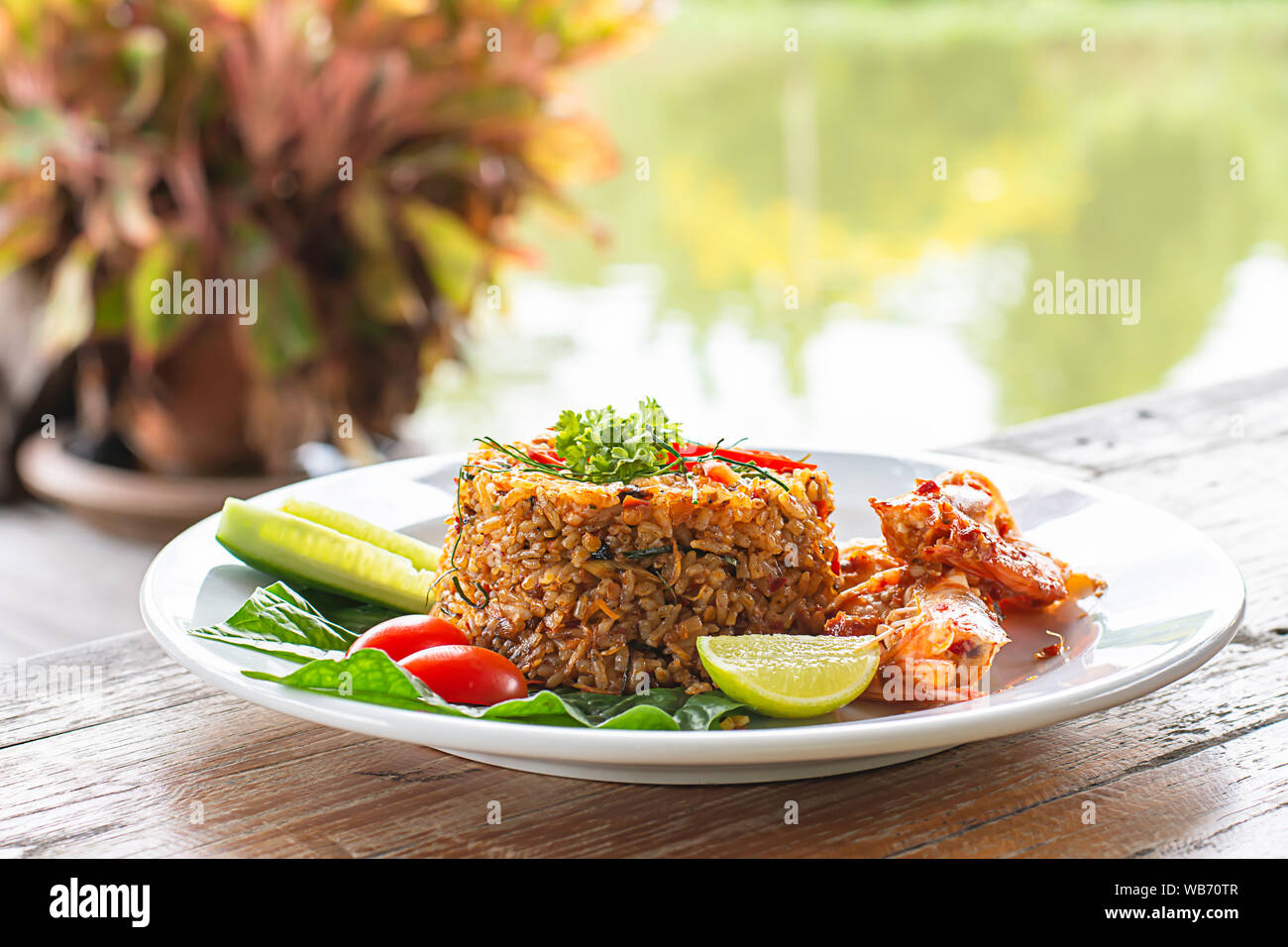 Riz frit aux crevettes sur table en bois , la nourriture épicée de style thaïlandais, les rivières et les arbres en arrière-plan. Banque D'Images