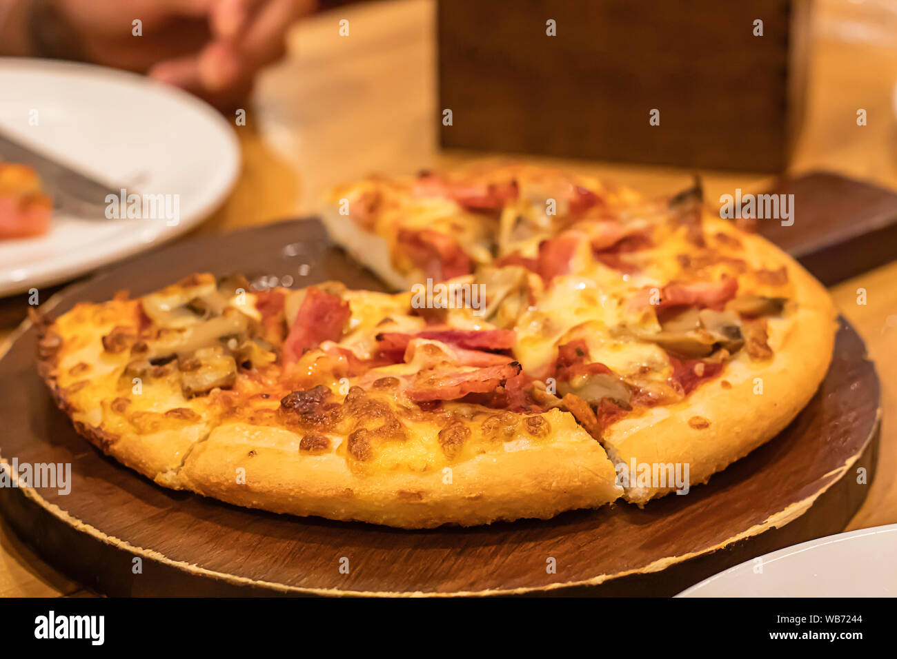 Pizza jambon sur le plateau en bois est placée sur la table. Banque D'Images