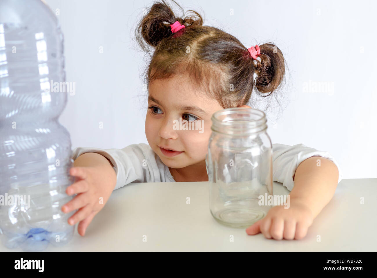 Enfant poussant la bouteille en plastique, holding glass jar. Pas de contenants en plastique, oui à des bocaux en verre. Image conceptuelle pour plastique anti campagne. Banque D'Images