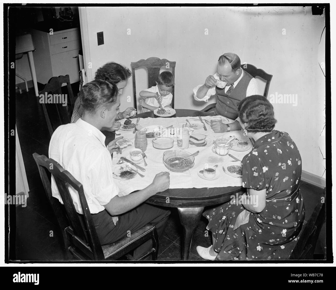 Première famille de s'installer en verdure. Washington, D.C. La première famille de circuler dans et vous installer à Greenbelt, MD, la réinstallation, la ville, l'Administration est M. et Mme J.M. Ashley, avec leurs enfants, Lynn, 18 ans, 16 ans et Dorma, Eddie, 4 ans. La famille d'Ashley sont montré avoir le premier repas dans la nouvelle maison. 10/2/37 Abstract/moyenne : 1 négatif : vitrage ; 4 x 5 in. ou moins Banque D'Images