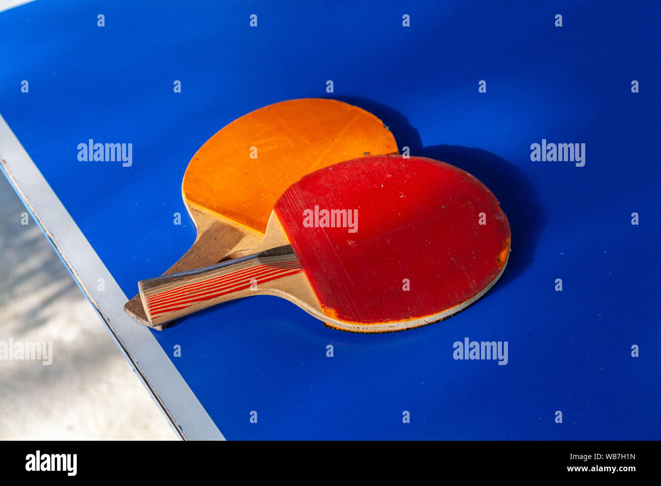 Close-up of orange et rouge deux raquettes de tennis de table allongé sur un tableau bleu Banque D'Images