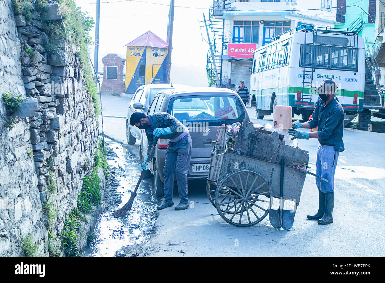 Shimla, Himachal Pradesh, Inde - Juillet 20th, 2019 : employé municipal balayer le système routier et de drainage avec balai et collecte des déchets, assainissement worke Banque D'Images