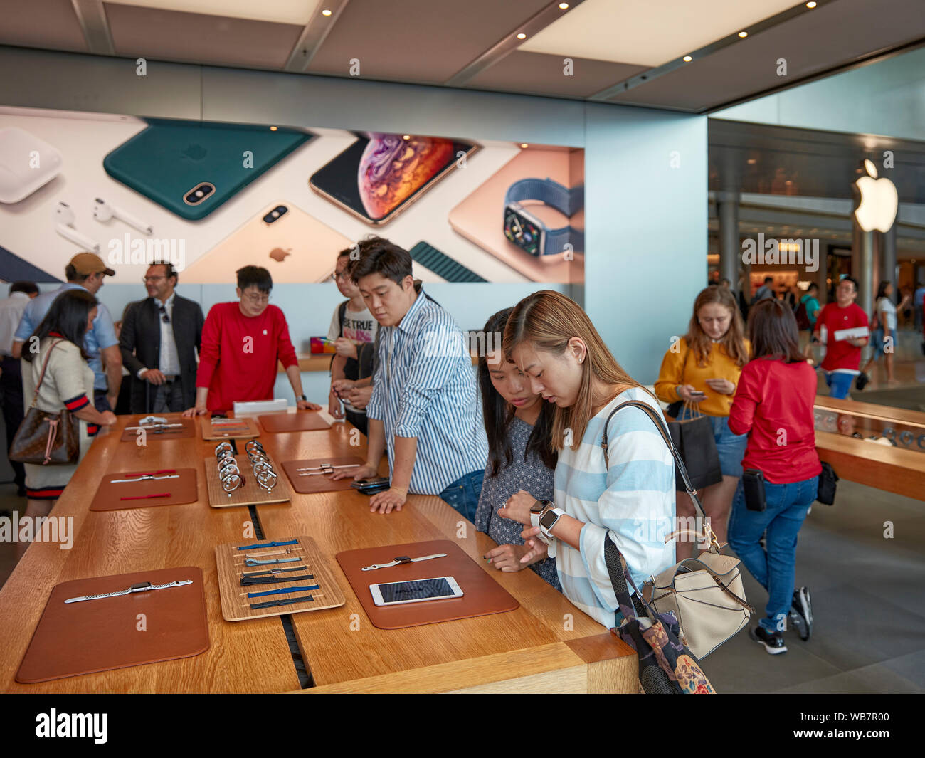 Jeunes femmes regardant de nouveaux modèles Apple Watch dans l'Apple Store. Central, Hong Kong, Chine. Banque D'Images