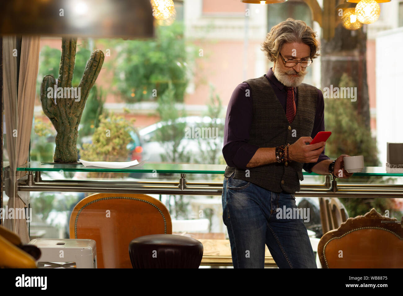 L'homme est concentré sur la lecture des nouvelles de son smartphone. Banque D'Images