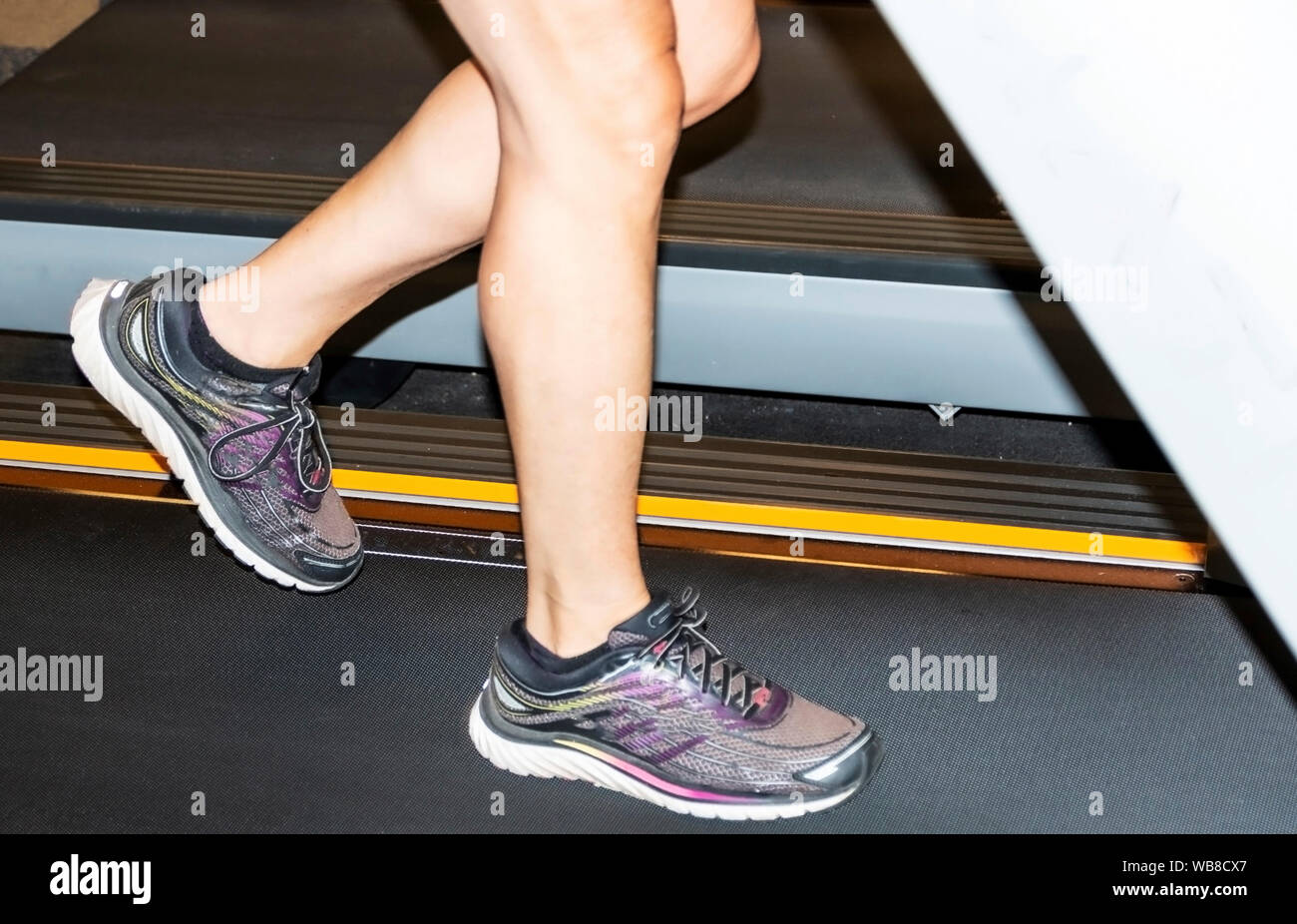 De près, vue latérale des jambes courir sur un tapis roulant à l'intérieur. Banque D'Images