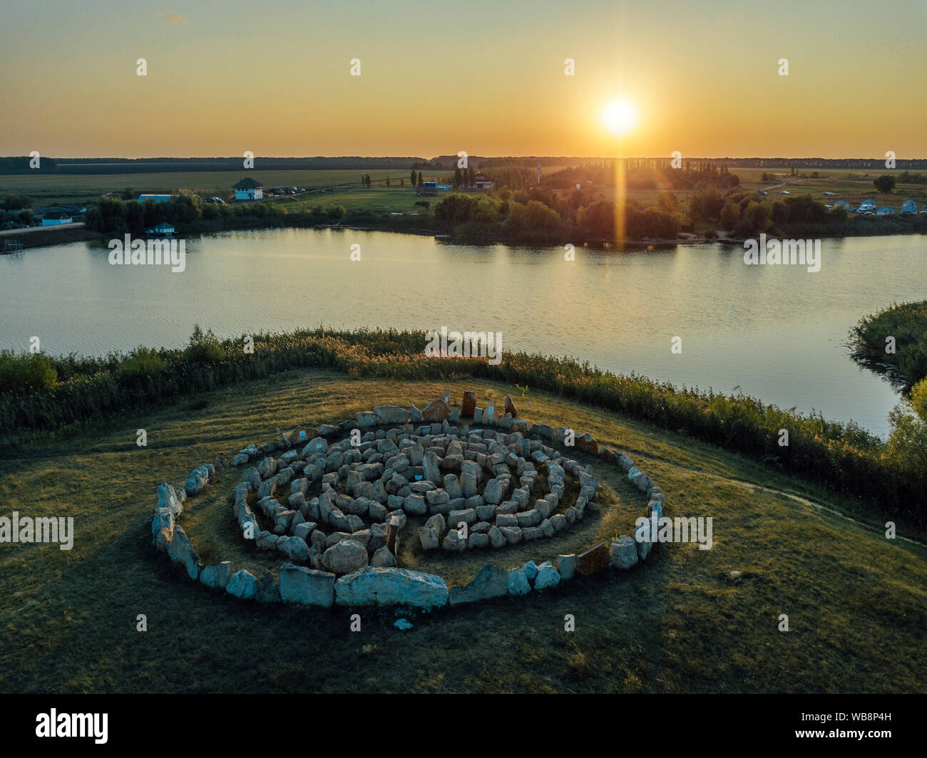Labyrinthe en spirale faite de pierres, sur le lac au coucher du soleil. Banque D'Images