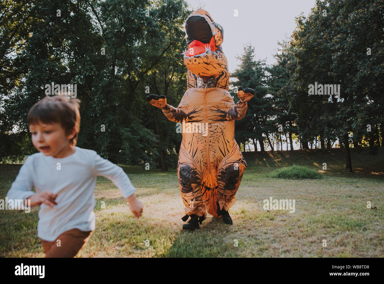 Père et fils à jouer au parc, avec un costume de dinosaure, s'amusant avec la famille piscine Banque D'Images
