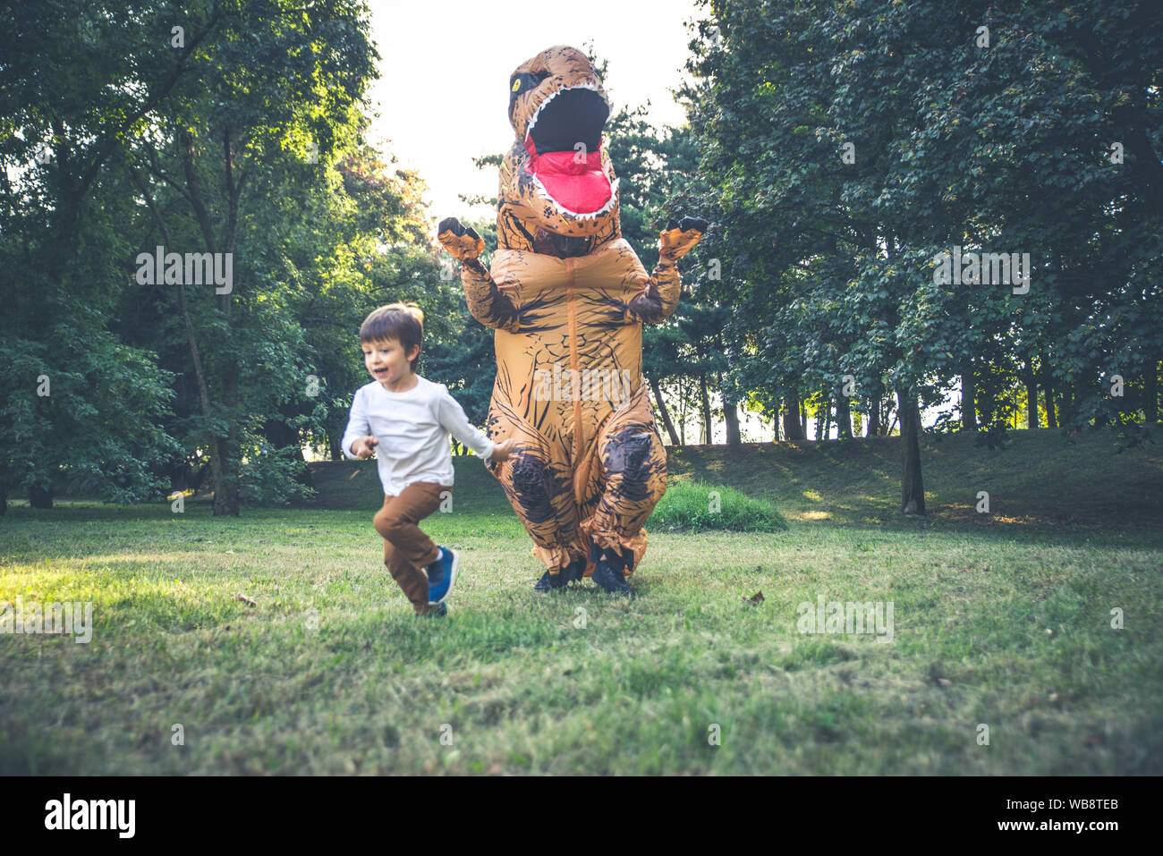 Père et fils à jouer au parc, avec un costume de dinosaure, s'amusant avec la famille piscine Banque D'Images