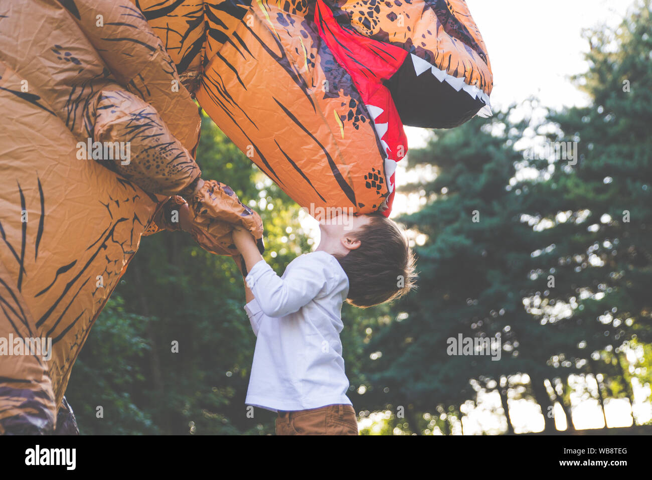 Père et fils à jouer au parc, avec un costume de dinosaure, s'amusant avec la famille piscine Banque D'Images
