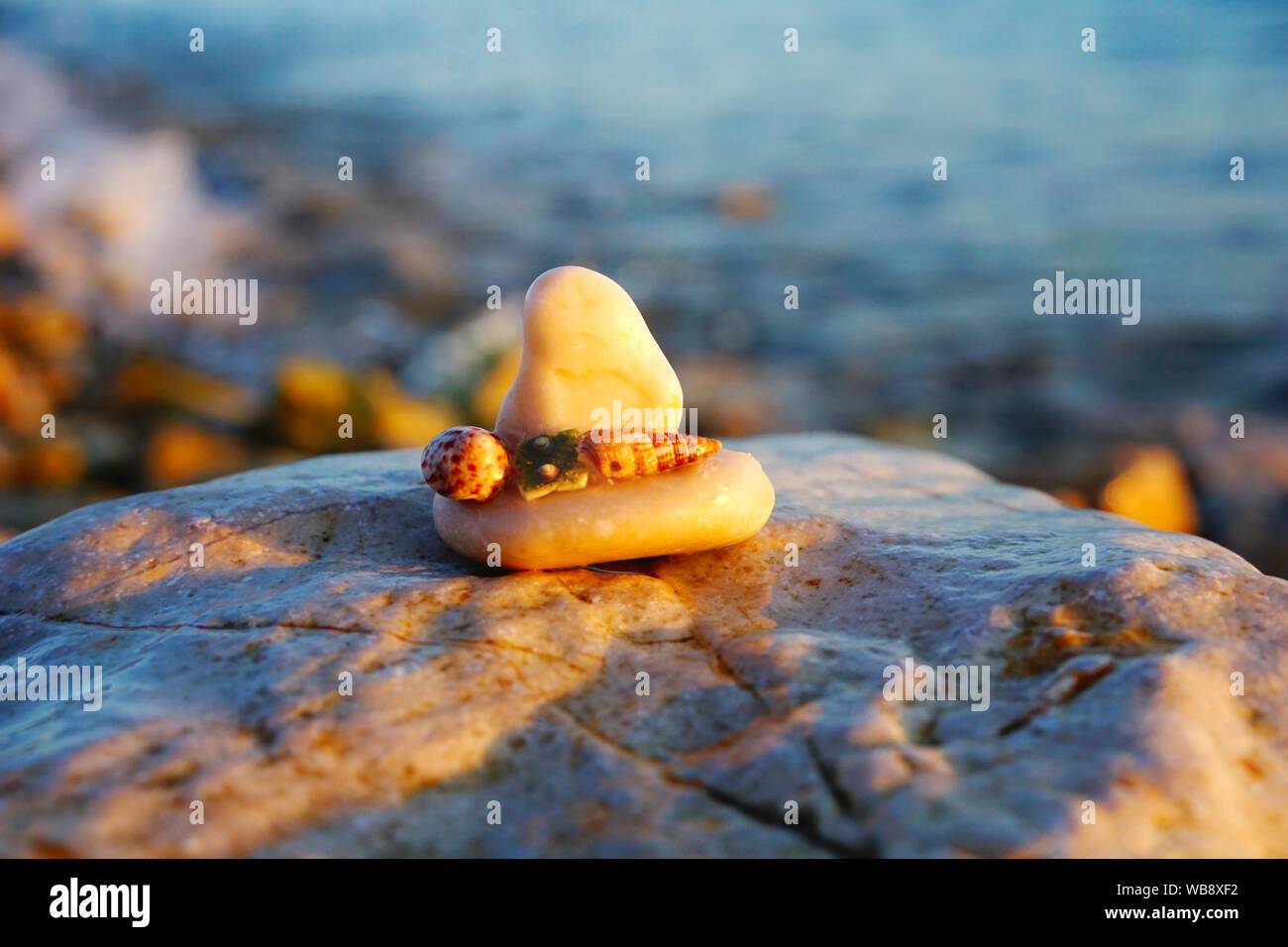 Arrière-plan de la mer. Voile faite de petites pierre sur la grosse pierre à l'arrière-plan flou seacoast et éclairés par les rayons du soleil au coucher du soleil Banque D'Images
