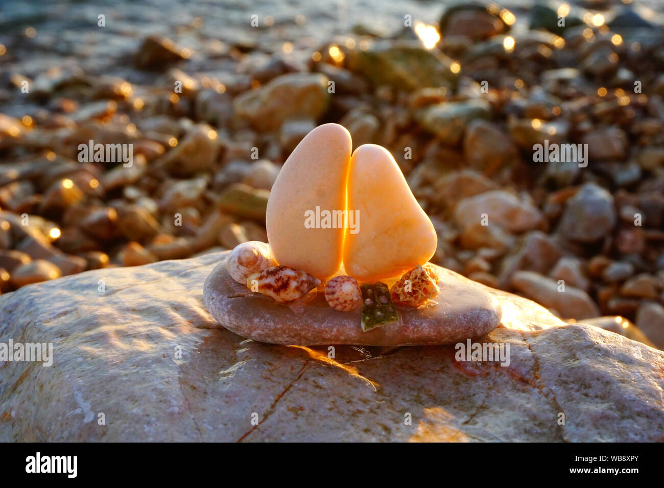 Souvenirs faits à la main sur la nature. Plage de galets, éclairé par le soleil au coucher du soleil avec de petits souvenirs bateau fabriqué à partir de cailloux et coquillages Banque D'Images