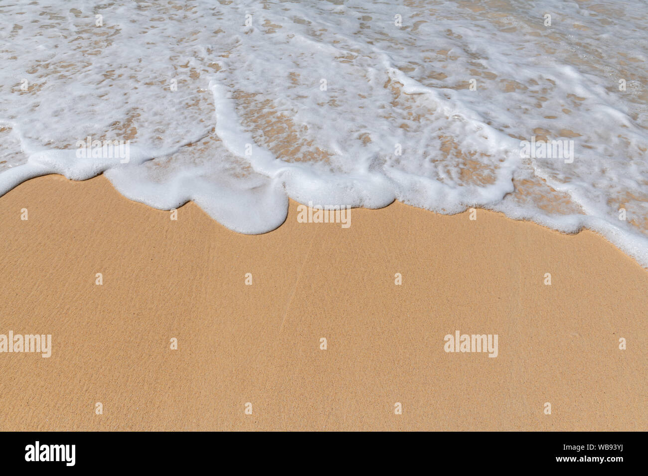 Les vagues de l'océan doux avec de la mousse sur la plage de sable. Banque D'Images