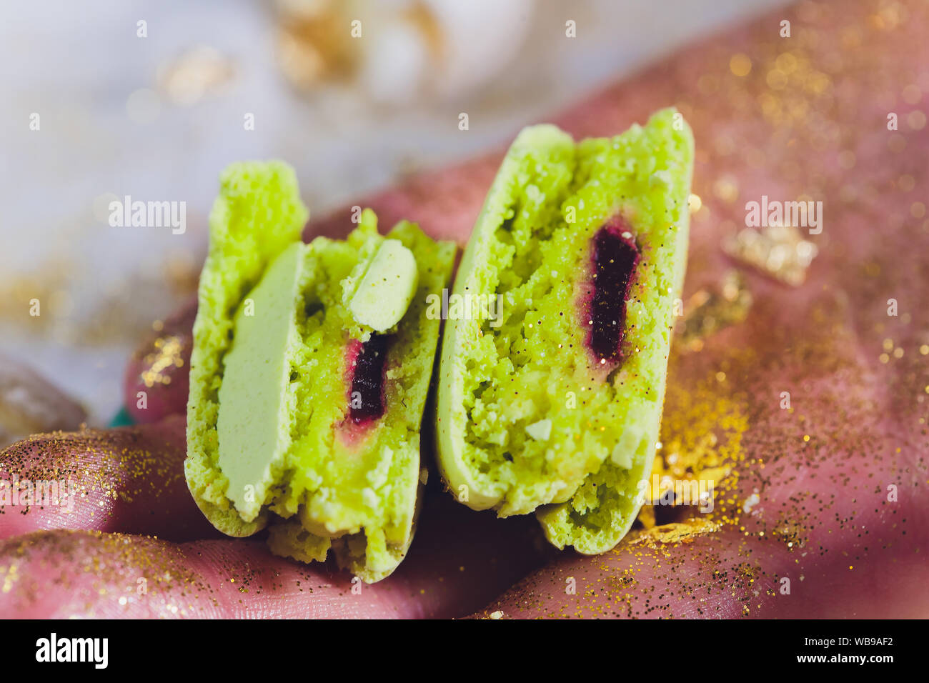 Main de femme en macarons brisés. Sur un fond blanc Banque D'Images