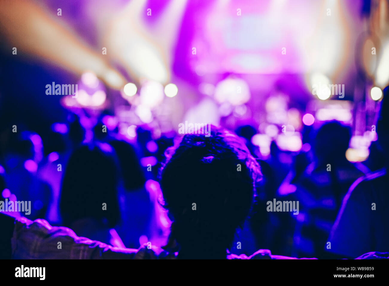 Les concerts foule pour assister à un concert, les gens silhouettes sont visibles, rétroéclairé par stade des lumières. Main levée et les téléphones intelligents sont visibles ici et là. Banque D'Images