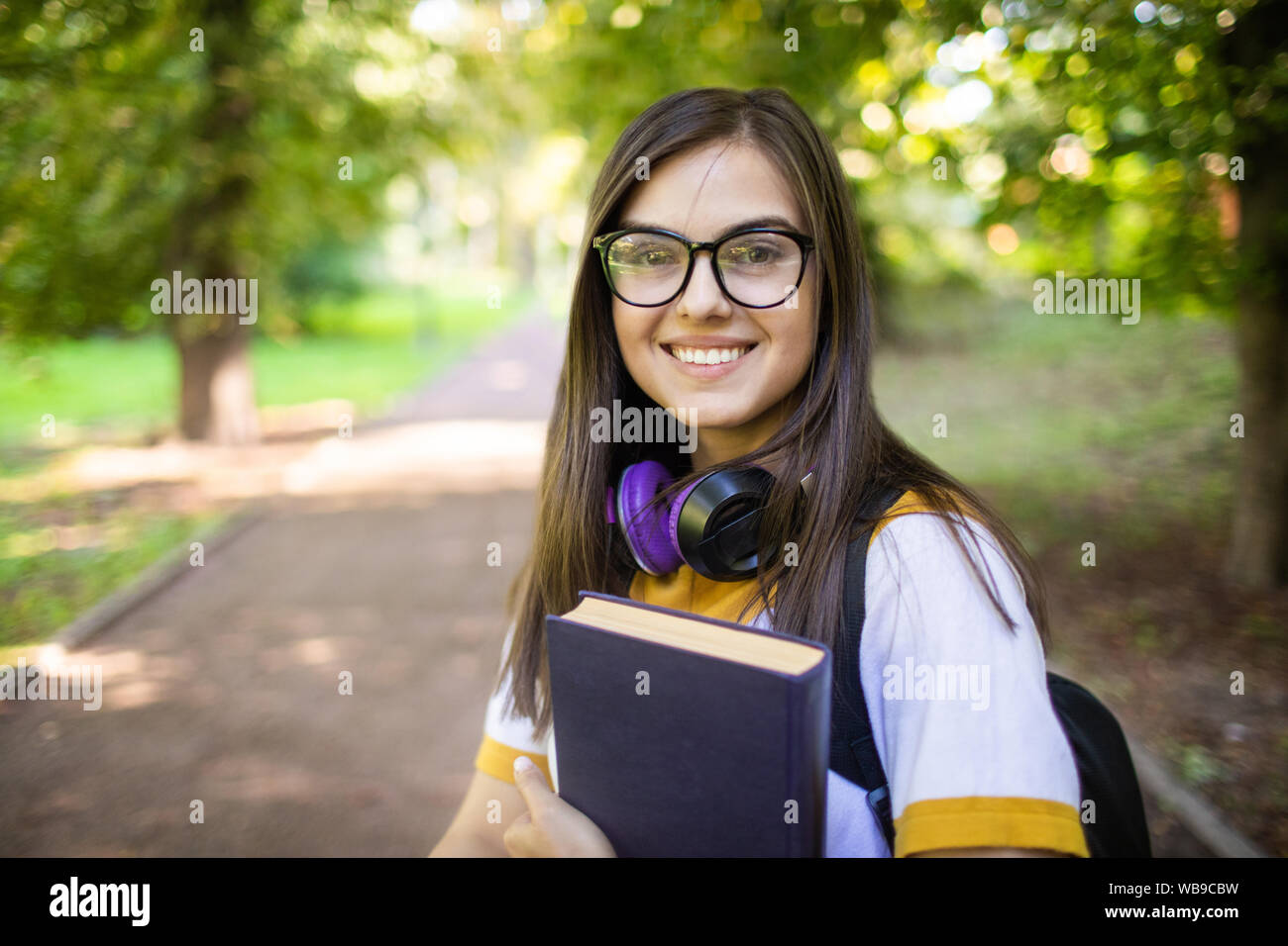 Portrait of a cute jeune étudiante fille sur son chemin aux classes à travers le parc du campus Banque D'Images