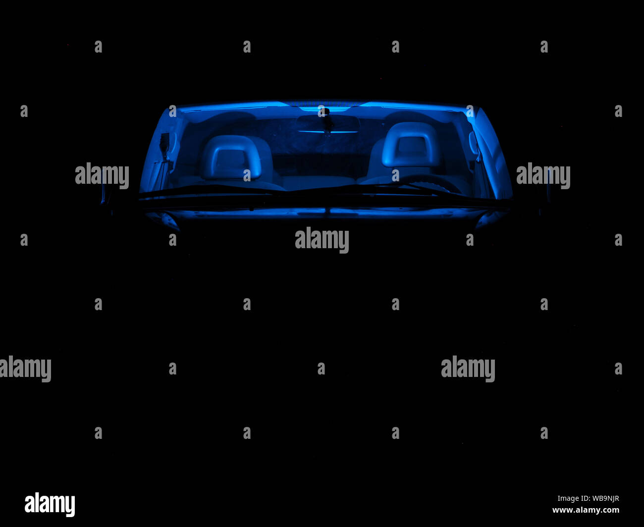 Une voiture avec néon bleu à l'intérieur de l'habitacle, sur une sombre nuit. Vue de face. Banque D'Images