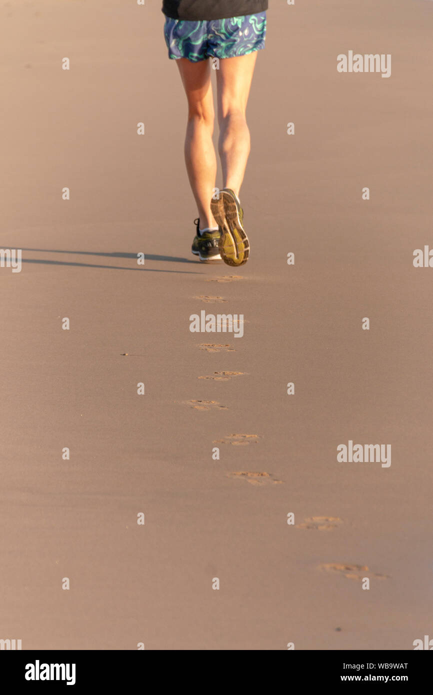 Une vue arrière d'un runner femmes faire son jogging sur la plage Banque D'Images