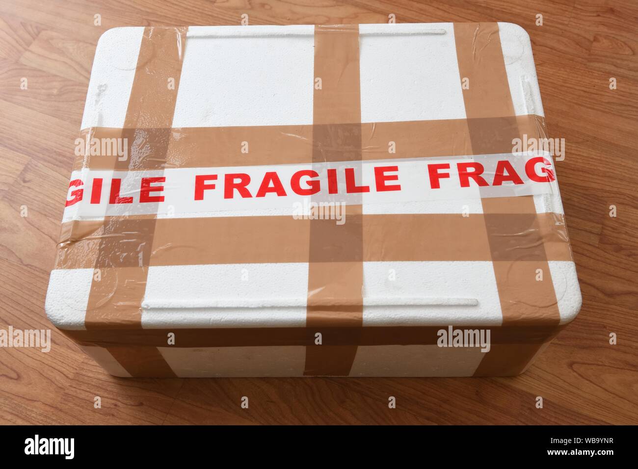 Une boîte en polystyrène blanc enveloppé dans une bande de colis et le mot 'fragile' écrit en rouge Banque D'Images