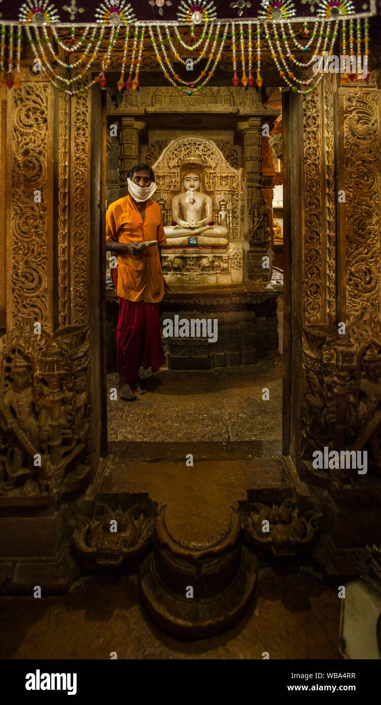 Un homme se tient dans la chambre intérieure de ce temple de Jain en tenant les offres monétaires dans un temple Jain au sein de Fort Jaisalmer, Inde. Banque D'Images