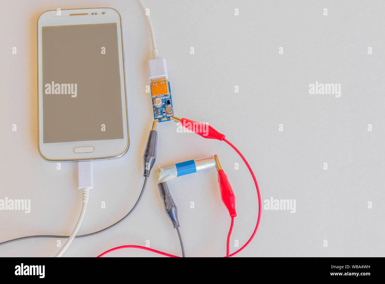 Le chargeur de téléphone portable à partir de la batterie 1,5 V, chargeur de batterie, circuit board, cordon d'alimentation, multi-usages, sur le fond blanc.Comment faire par yo Banque D'Images