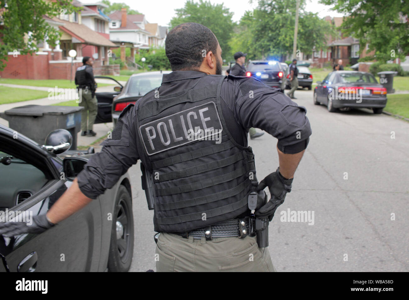 Service de police de Detroit, officier des opérations spéciales tiroirs son arme alors qu'il se prépare à aborder une maison, qu'ils en ont l'air d'un suspect, Detroit, Michigan, USA Banque D'Images