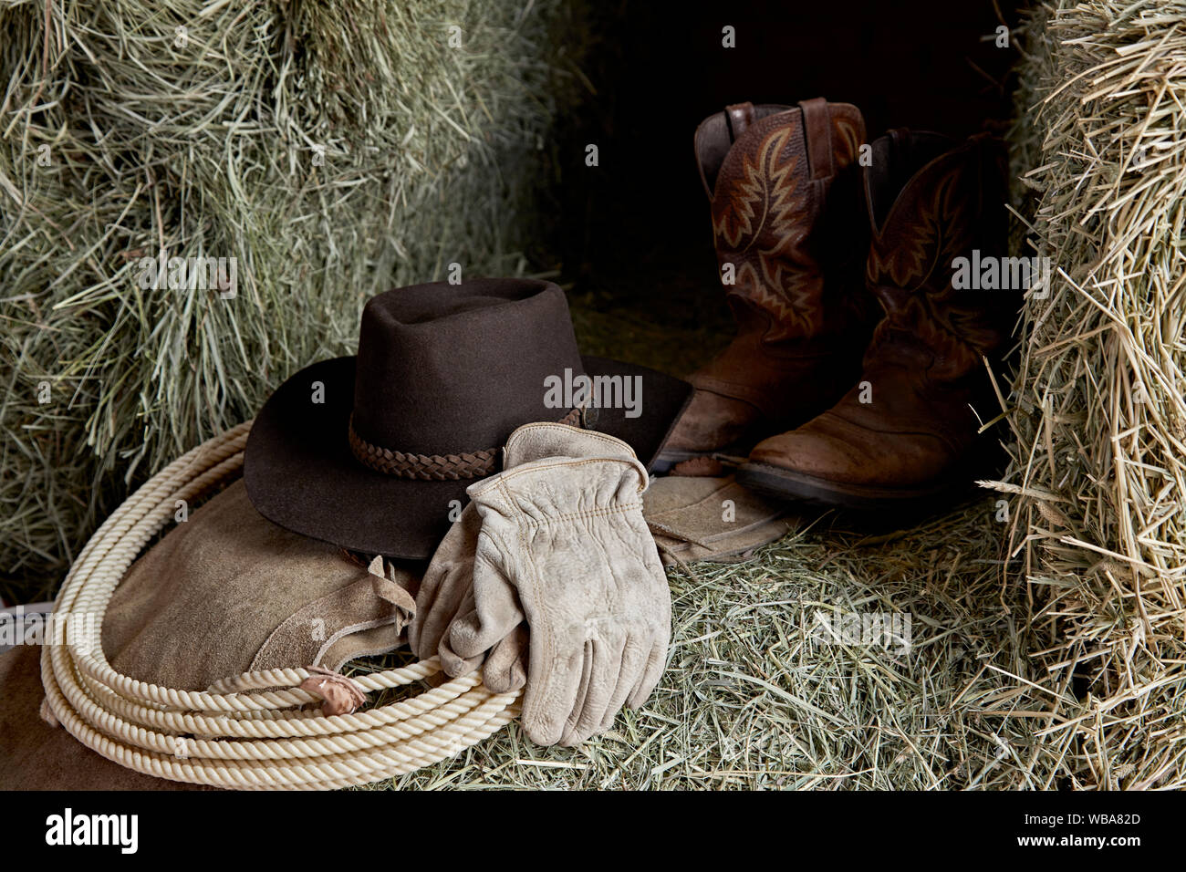 Chapeau de Cowboy de l'ouest avec des gants en cuir, bottes de cow-boy et  bottes, et une corde de roper sur le foin dans une grange Photo Stock -  Alamy