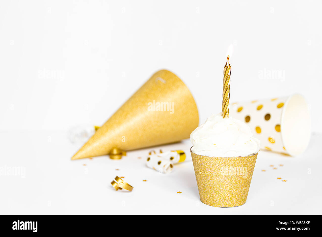 Cupcake avec cierge allumé et des accessoires dans la couleur d'or. Banque D'Images