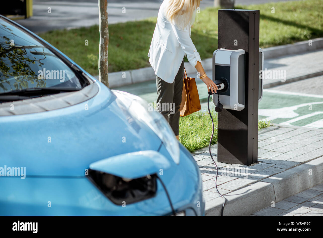 Portrait de brancher des armes à feu de charge électrique dans la station d'essence sur le parking en plein air Banque D'Images