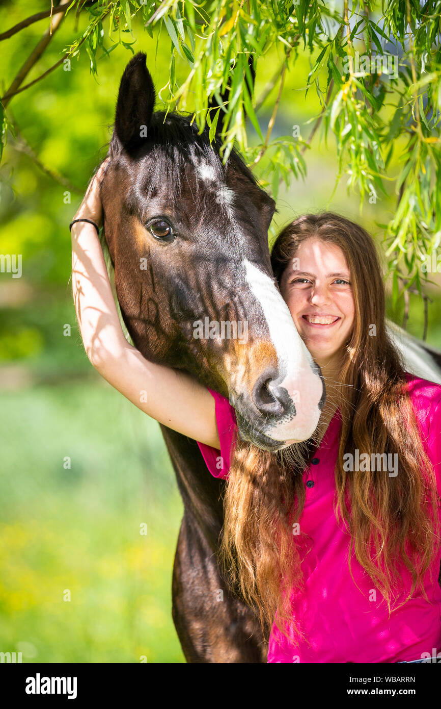 Cheval domestique. Pinto (Poney irlandais) smooching femme avec des brindilles de saule unter. La Suisse Banque D'Images