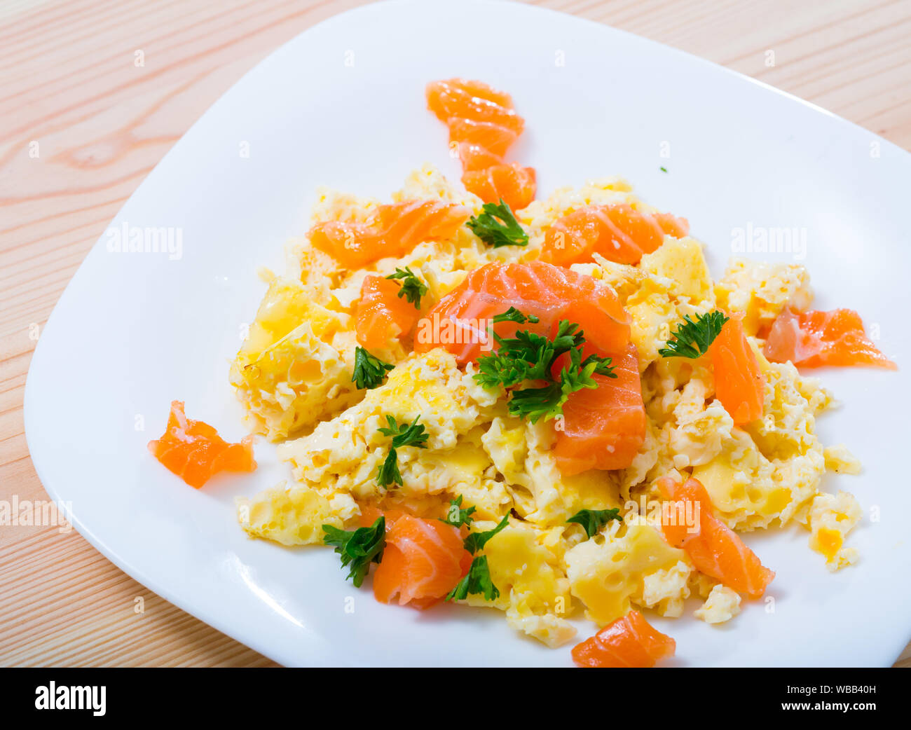 Une cuisine norvégienne. Des œufs brouillés avec du saumon garni de vert frais sur le plat blanc Banque D'Images