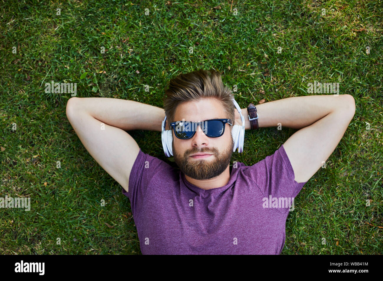 L'homme et l'écoute de la musique tout en étant allongé sur le sol à  l'extérieur dans des lunettes de soleil Photo Stock - Alamy
