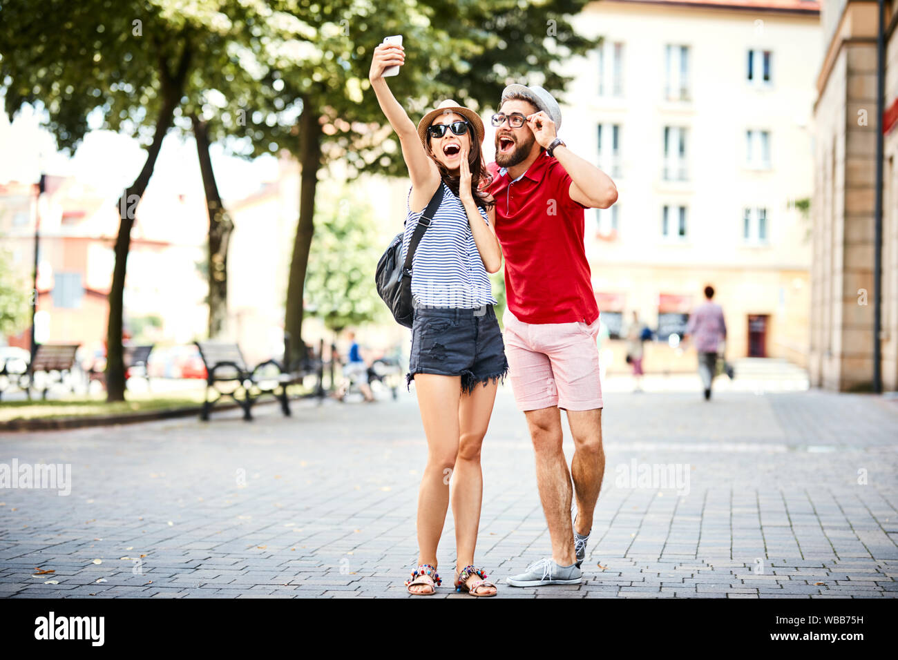 Jeune couple en tenant ensemble tout en selfies sur promenade dans la ville au cours de l'été Banque D'Images