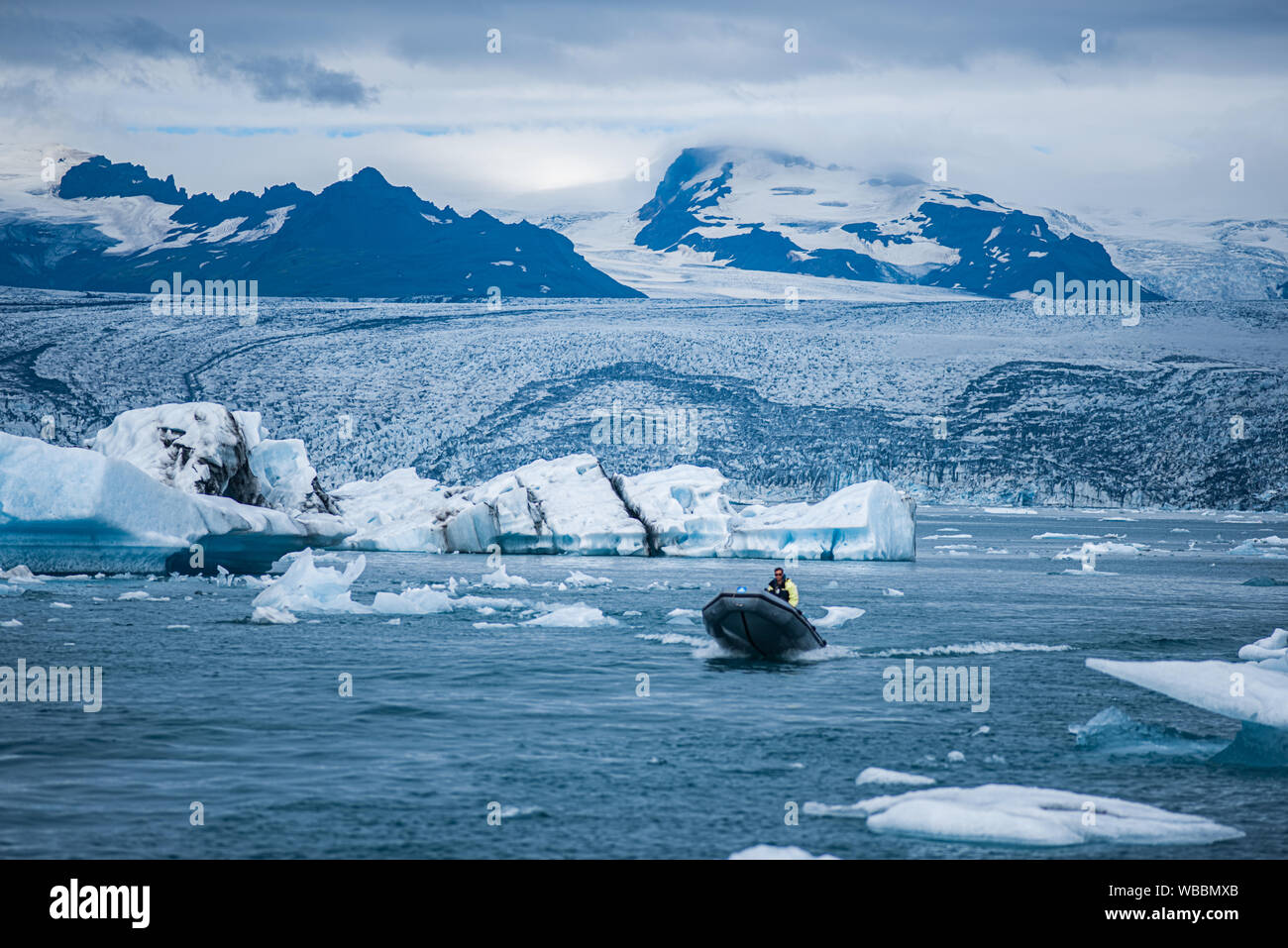 Petit bateau naviguant sur le lac Jökulsárlón parmi les morceaux de glace flottante, l'Islande Banque D'Images
