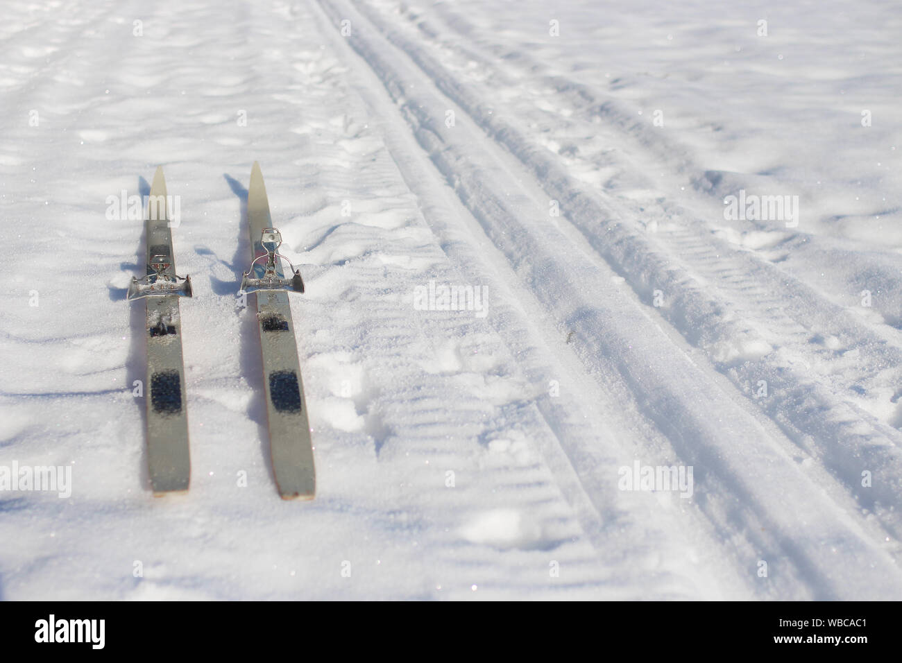 Croix de bois vieux skis de fond et une piste de ski enneigées vide avec ciel bleu clair Banque D'Images