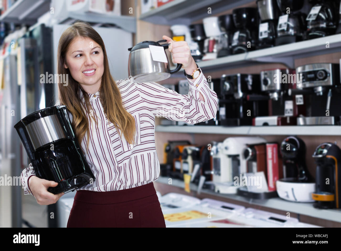 Jeune femme le choix de cafetière dans la boutique Banque D'Images