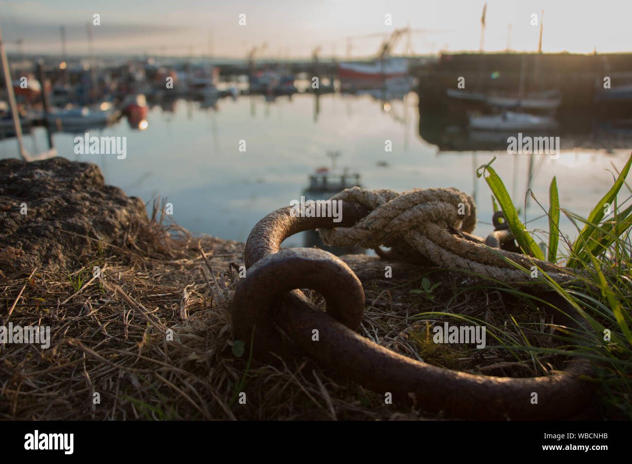 Chaîne d'amarrage rouillées au lever du soleil avec le port de Newlyn en arrière-plan, paysage Banque D'Images