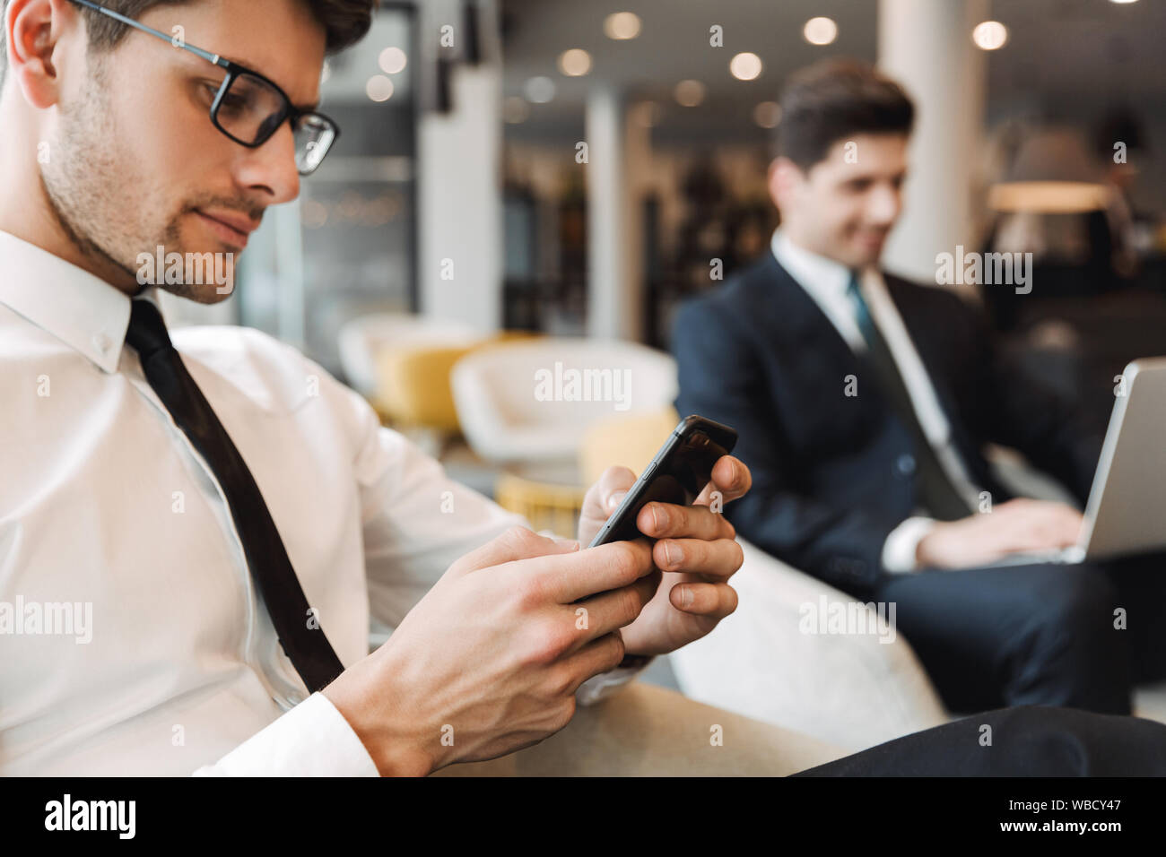 Image d'un concentré à l'intérieur d'affaires collègues dans le centre d'affaires office à l'aide de téléphone mobile et ordinateur portable. Banque D'Images