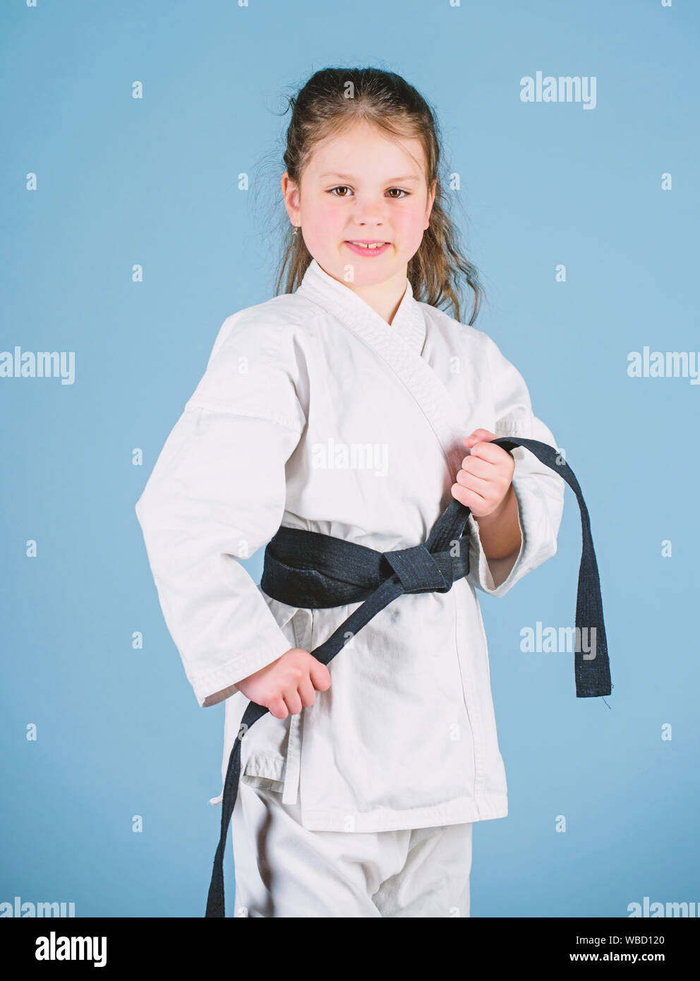 Le sport et l'activité. Kid forte et confiante. Petit enfant fille en kimono blanc avec ceinture. Karate fighter prêt à combattre. Karate sport concept. Compétences d'auto-défense. Le karaté donne un sentiment de confiance. Banque D'Images