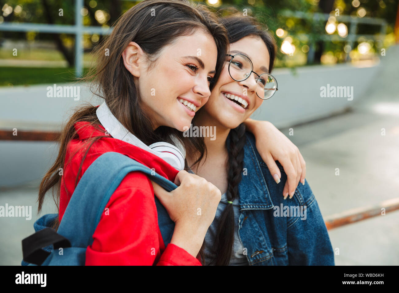 Image de deux filles gaie habillés de vêtements en denim et rire ensemble tout en serrant walking in park Banque D'Images