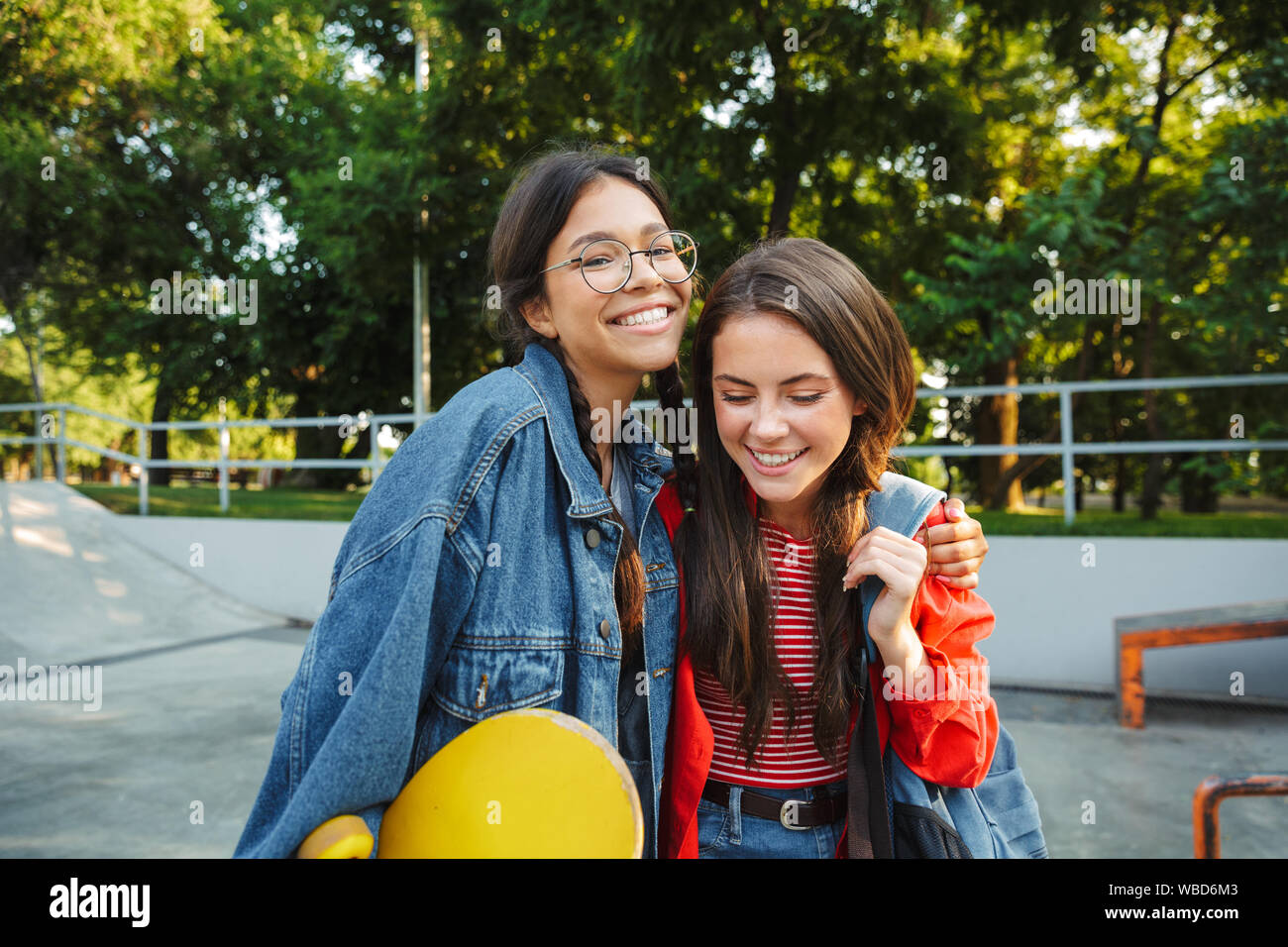 Image de deux filles heureux vêtus de denim wear smiling and hugging ensemble tout en maintenant en skateboard skate park Banque D'Images