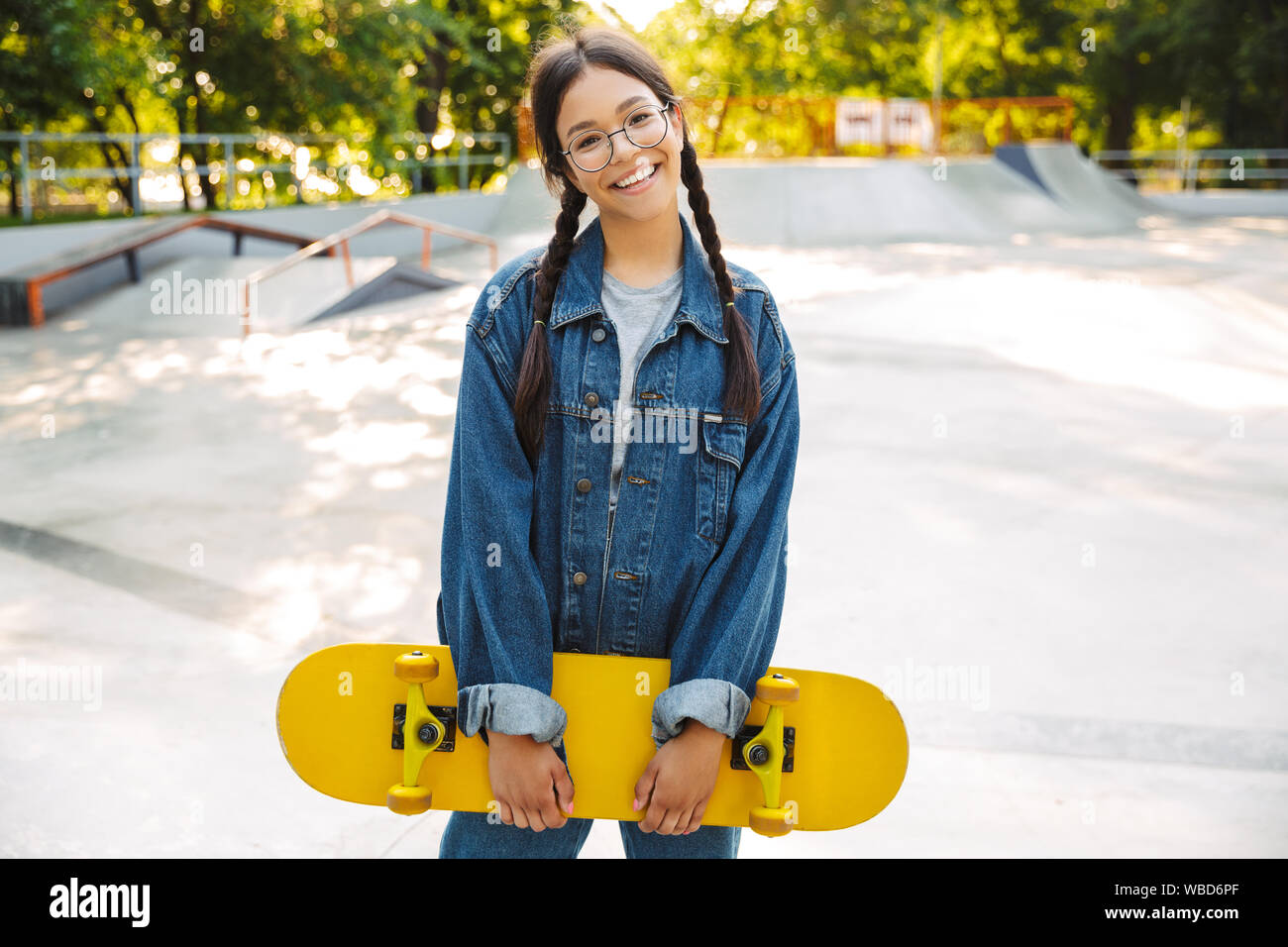 Image de fille joyeuse vêtus de vêtements en denim de sourire et de se  réjouir en maintenant en skateboard skate park Photo Stock - Alamy