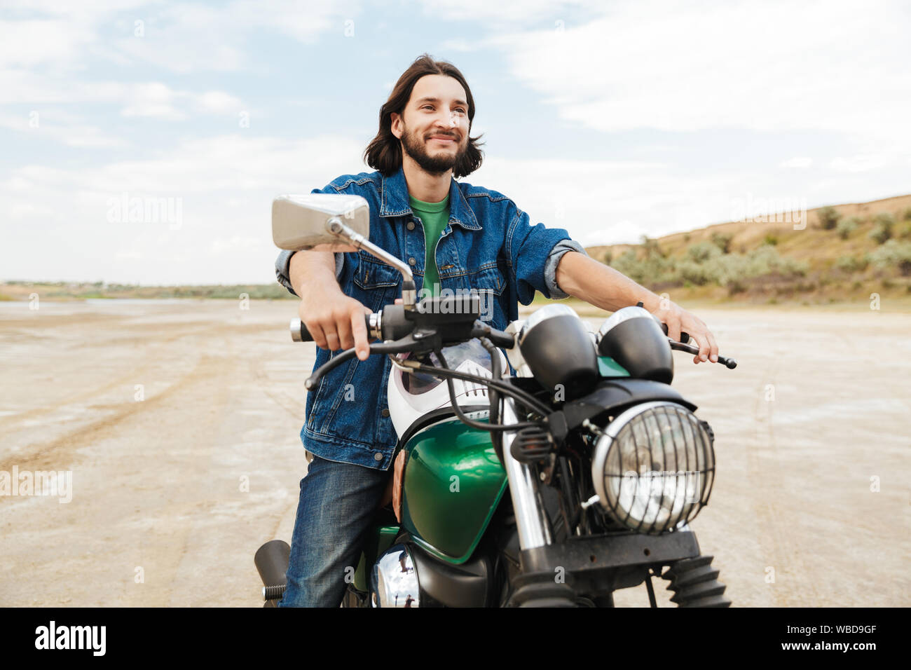 Handsome young man wearing tenue décontractée assis sur une moto à la plage Banque D'Images
