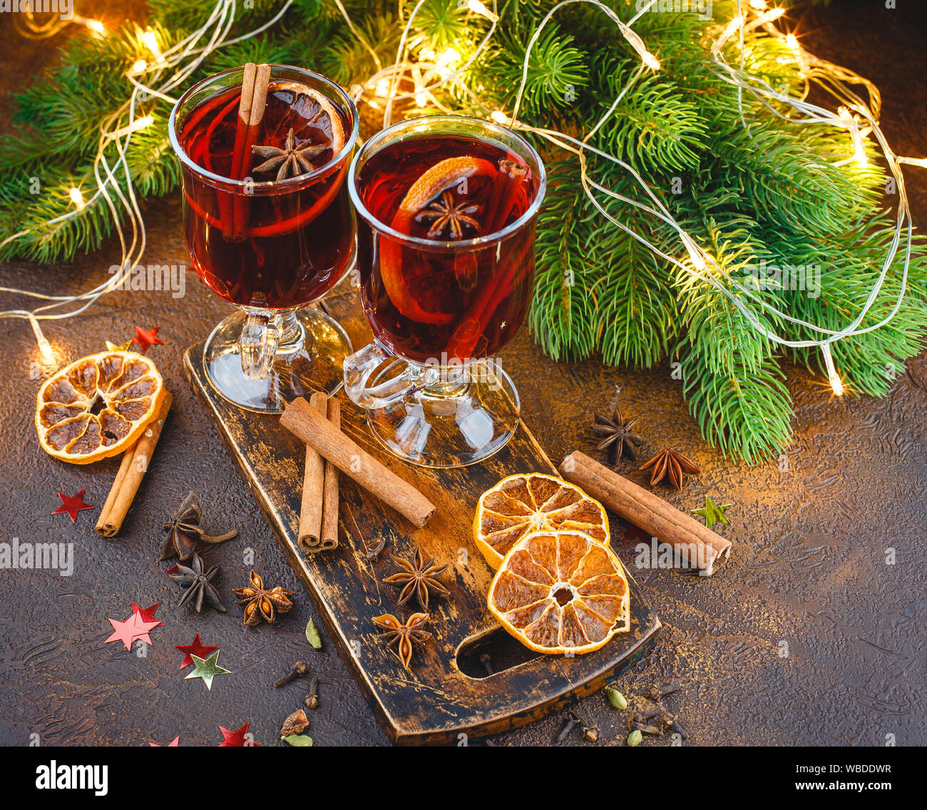 Tasses en verre de vin chaud avec des épices et des morceaux d'orange sèche sur planche à découper en bois sur fond sombre. Noël traditionnel verre Banque D'Images