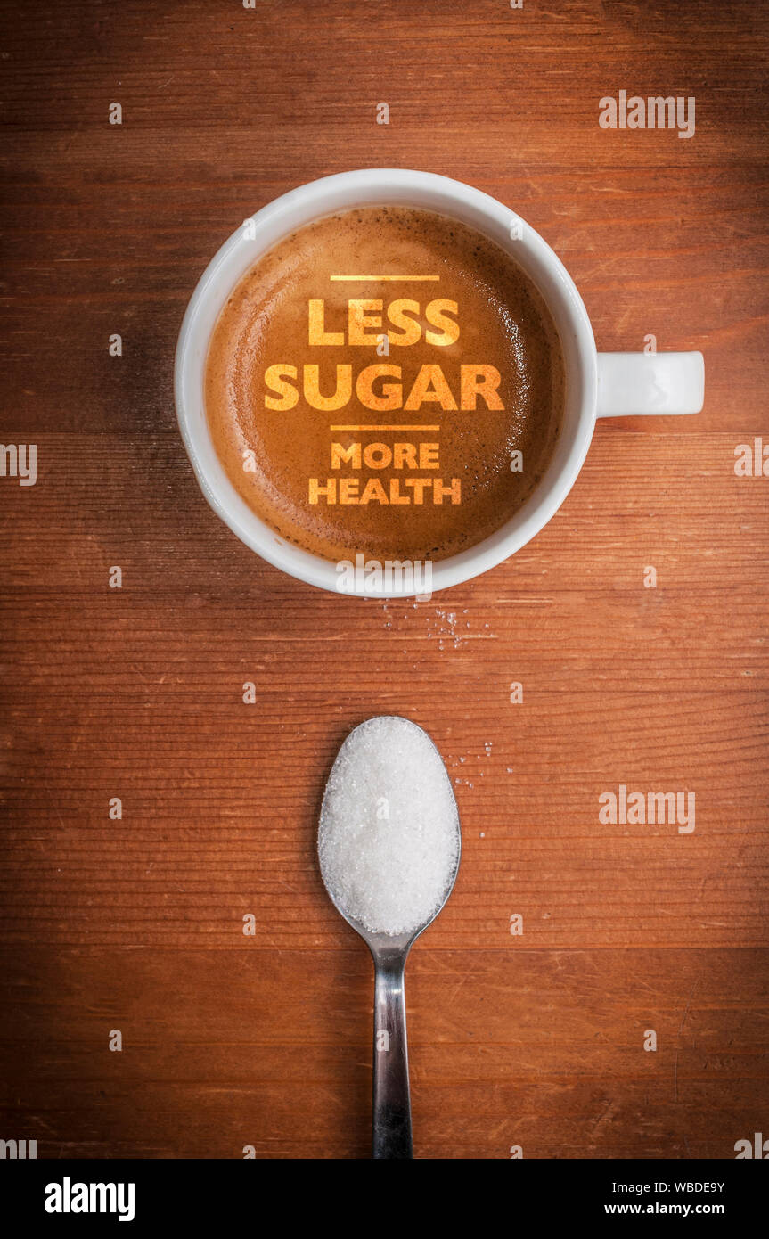 Concept de soins de santé : une tasse de café avec un texte moins de sucre plus de santé sur table en bois et une cuillère pleine de sucre blanc Banque D'Images