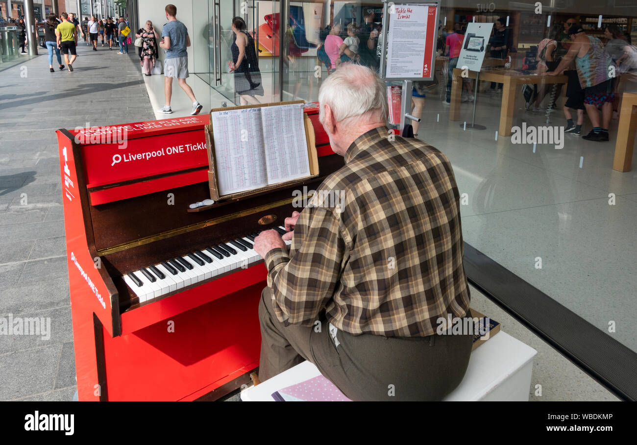 Senior male jouer a Liverpool un piano rouge Banque D'Images