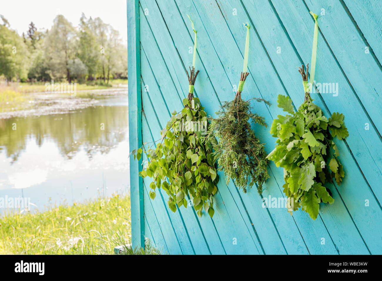 Produits frais, essence : chêne, bouleau, chêne et juniper tree sauna fouets manches pendent et le séchage sur sauna maison wall par beau lac naturel. Sauna Traditionnel finlandais Banque D'Images