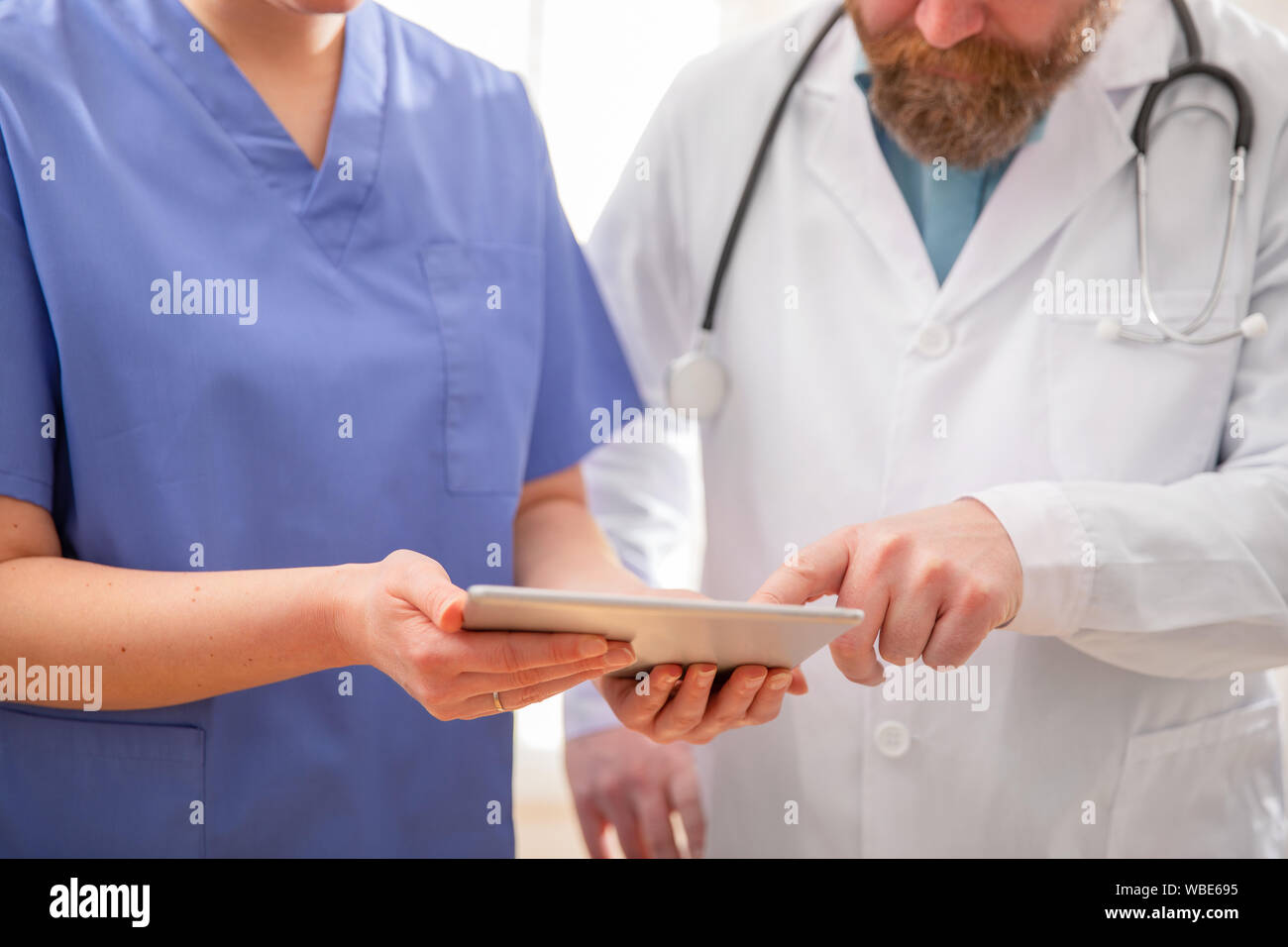 Doctor and nurse discussing patients essais a tablet computer in hospital Banque D'Images