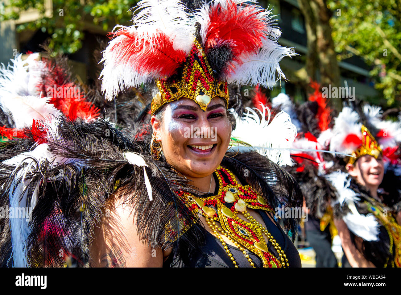 26 août 2019 - Danseuse habillés dans une plume coiffe samba smiling at Notting Hill Carnival sur une maison de banque lundi, Londres, UK Banque D'Images